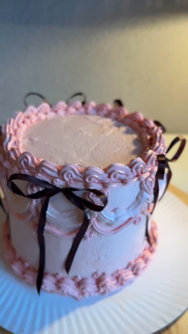 Vintage-Torte mit rosa Buttercreme-Bögen und dunklen Schleifen
