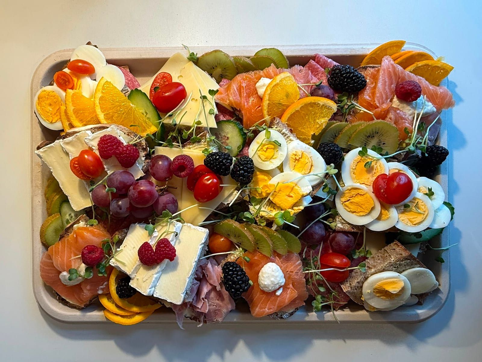 Große Frühstücksplatte mit Käse, Räucherlachs, Eiern, Obst und Beeren