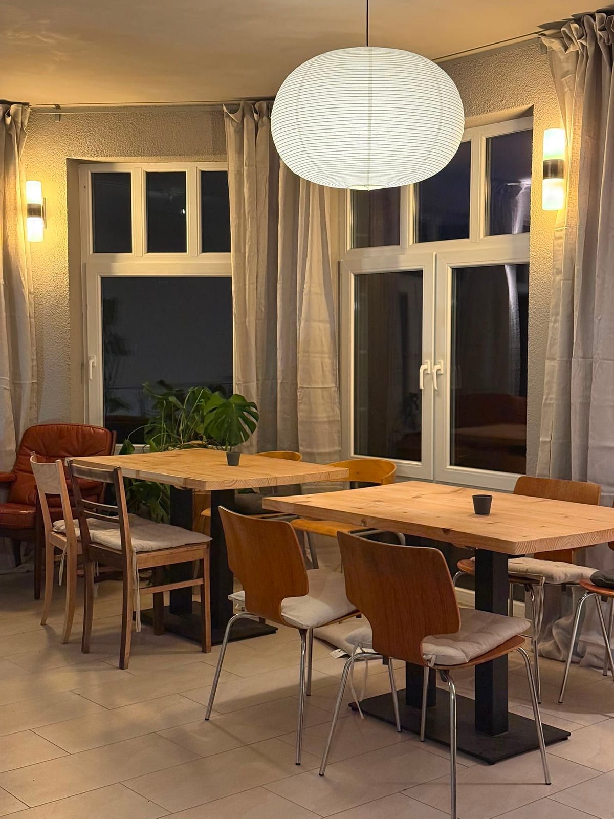Gastraum am Abend mit warmem Licht und gedeckten Holztischen