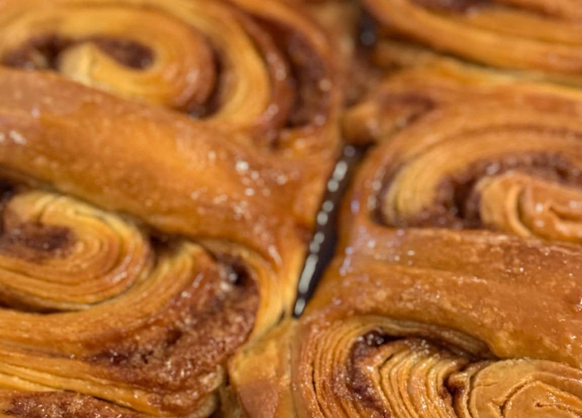 Frisch gebackene Sauerteigschnecken dicht an dicht, glänzend vom Ofen