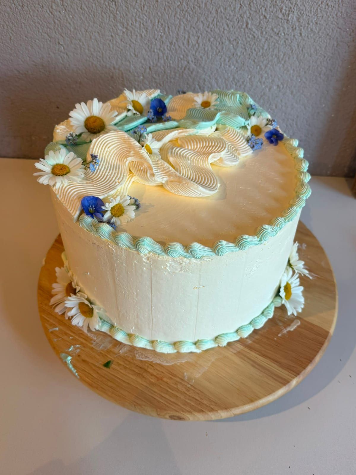 Auftragstorte mit heller Creme und echten Wiesenblumen